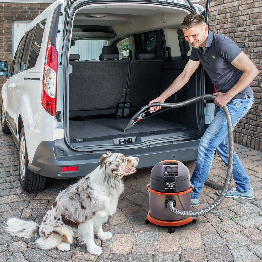 THOMAS Aqua Fleckwasher, мужчина моет салон автомобиля пылесосом, рядом сидит большая собака